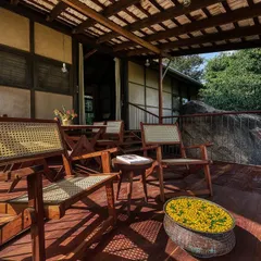 The wooden deck of the prefab cottage is an essential living space, furnished with classic planters' chairs for enjoying the view and the tropical climate.