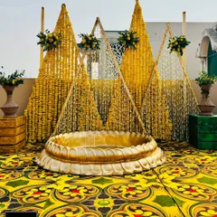 For this rooftop Haldi, I created a unique backdrop with pyramids of 'genda phool' garlands and a large brass urli in the center for the bride to sit in, all set against a vibrant printed carpet.