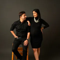 A stylish couple's portrait. The mom-to-be wears our chic black turtleneck dress, creating a timeless and coordinated look with her partner.