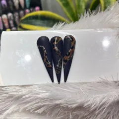 This design features a fierce snake with a leopard print skin, slithering over a matte black stiletto nail. A perfect example of combining different textures and patterns.