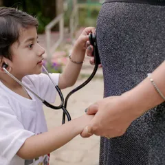A young boy listens to his mother's baby bump with a stethoscope, a heartwarming moment of anticipation for the new arrival.