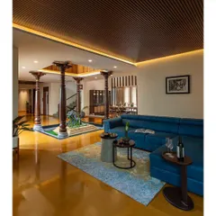 The family living area, seen from the courtyard with its traditional Chettinad pillars. The juxtaposition of the modern blue sofa with the ancient architectural forms defines our unique design language.