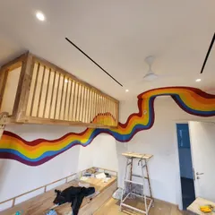 A view from the front, showing how the rainbow wave flows up and over the doorway, adding a playful and minimal aesthetic to the room.