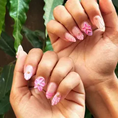 A beautiful shot of the 3D floral nails against a natural green background. This set features a mix of textures, including a sculpted flower, a shell-like texture, and gold stud accents.