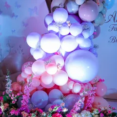 A beautiful cascade of pink, purple, and white balloons mixed with fresh flowers. This combination of textures creates a soft, organic, and luxurious feel perfect for an enchanted garden party.