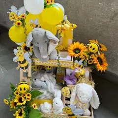 A tower of joy for a new arrival. This multi-tiered "bee-themed" hamper is buzzing with excitement, filled with plush toys, baby essentials, and cheerful sunflower and balloon accents.