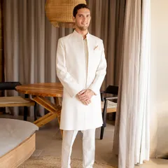 A picture of refined elegance. For this beach wedding, we styled the groom in a custom ivory sherwani by Lalit Laungani, a look that is both sophisticated and perfectly suited to the serene coastal setting.