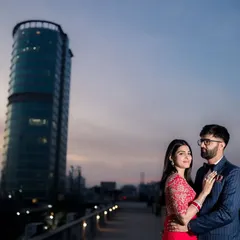 Your story set against the city's evening glow. This cinematic portrait on a rooftop uses the urban landscape and twilight sky to create a dramatic and modern pre-wedding photograph.