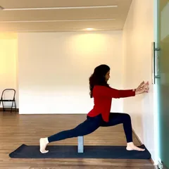 The wall and a yoga block are excellent props for learning alignment in poses like the high lunge. Using the wall for support helps stabilize the pose, allowing you to focus on opening the chest and deepening the hip stretch.