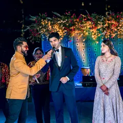 Capturing the interactive and fun moments of a Sangeet night, as the event host engages with the groom on stage.