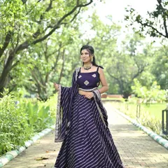 A deep purple lehenga featuring elegant silver leheriya stripes. This outfit combines a classic pattern with a rich color, making it a sophisticated choice for any festive occasion.