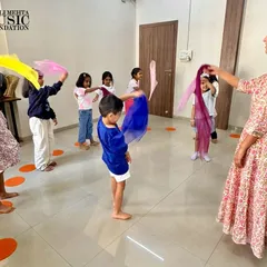 A teacher guides students in a group scarf activity. This demonstrates how you will learn to lead a class in coordinated movements that reinforce musical concepts like tempo and dynamics in a visually engaging way.