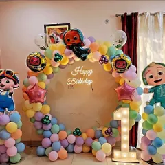 This Cocomelon first birthday setup includes a full ring backdrop, character cutouts, and a light-up marquee number '1'. The colorful balloons create a playful atmosphere for the little one.