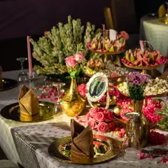An elegantly set dinner table at a wedding reception, featuring golden plates, floral arrangements, and soft candlelight.