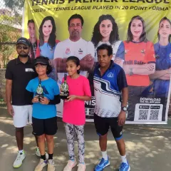 Two of our young female players proudly display their trophies alongside our coaches. We are committed to developing strong female athletes in our junior tennis programs.