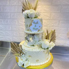This three-tier wedding cake for Krish and Kripa features intricate stencil work, gold leaf, and beautiful dried botanicals. The middle tier is a clear separator filled with lights and flowers for a modern touch.
