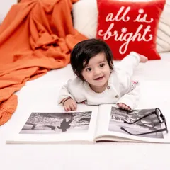 A happy baby enjoying story time. This candid shot captures a genuine smile and a moment of quiet fun, showing the beauty in everyday activities.