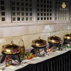 This is a classic example of my buffet setup, featuring a line of gleaming brass chafing dishes against a black-draped table. The arrangement is clean, elegant, and ready to serve a delicious feast for a formal event.