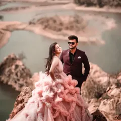 For pre-wedding shoots, I love finding epic locations like this one. The couple stands on a rocky cliff overlooking the water, creating a truly breathtaking and romantic image. The stunning pink ruffled gown is from my rental collection.