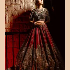 A dramatic, full-length bridal portrait using light and shadow to create a powerful and elegant image of the bride in her stunning red lehenga.