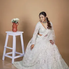 A full-length view of the white lehenga, showing the beautiful all-over embroidery and the sheer, detailed dupatta.