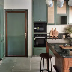 Here, you can see how the kitchen door was designed to match the cabinetry, creating a seamless look. Every detail, from the built-in appliances to the bar stool at the island, is chosen to create a cohesive and welcoming atmosphere.