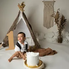 A stylish boho-themed cake smash for a little explorer turning one. This setup features a teepee, macrame details, and earthy tones for a minimalist yet whimsical first birthday photoshoot. It’s all about celebrating this big milestone with fun, laughter, and a little bit of mess.