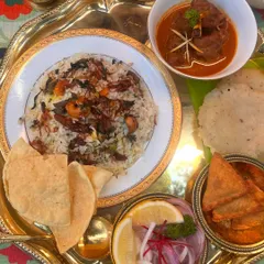 A closer look at our Eid platter. Aromatic biryani, a hearty mutton curry, crispy pappadams, and a cooling raita. Every element is carefully prepared to create a harmonious and satisfying meal.