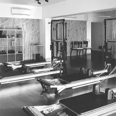 A black and white shot of our studio space, highlighting the clean lines of the reformers and the calm, focused atmosphere we cultivate.