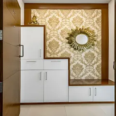This entryway design combines functionality with traditional elegance. The white storage unit includes a shoe cabinet and drawers, set against a classic damask wallpaper for a touch of luxury.