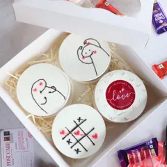 A top-down view of 'The Flirt Box', showing the four tub cakes with their fun designs, all packed up and ready to gift.
