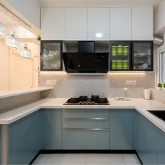 A modern U-shaped kitchen in a calming pastel blue and white. The geometric backsplash adds a contemporary touch, while the open pass-through counter connects it to the dining area.