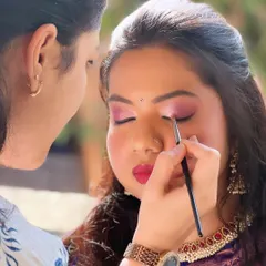 A behind-the-scenes shot of me creating a vibrant look with pink eyeshadow and a red lip for a wedding guest.