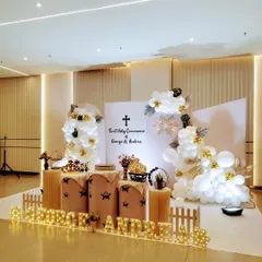 Another angle of the elegant First Holy Communion decor, showcasing the clean lines of the backdrop and the thoughtful placement of decorative elements like crowns and a miniature bicycle.