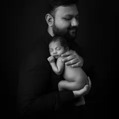 A similar moment with different lighting, creating a more classic, low-key portrait that emphasizes the father's protective embrace.