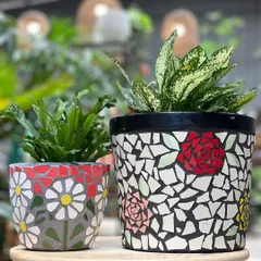 A closer look at our mosaic planters. The one on the left features a daisy pattern, while the larger one on the right has abstract rose designs. They are perfect for housing indoor plants like ferns and aglaonema.
