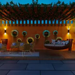 This twilight view captures the magical ambiance of a well-lit terrace. The design features a large pergola with climbing plants, a cozy hanging swing, and illuminated planters, creating an enchanting space for evening relaxation.