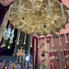 A magnificent oversized Rajasthani umbrella with intricate gold embroidery, serving as a unique and grand chandelier-like installation.