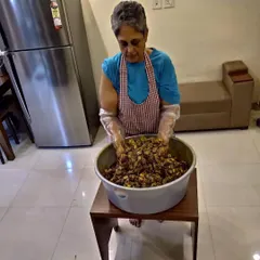 Here I am, mixing a large batch of my Aam ka Achaar by hand. This ensures that every single piece of mango is evenly coated with the masala. It's hard work, but I love every moment of it.