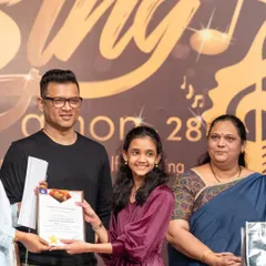A student receiving her certificate and prize at our 'Singathon' event. These competitions are a fantastic platform for children to showcase their hard work.