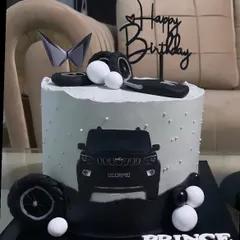 This cake is designed for a Mahindra Scorpio lover, featuring the new logo and an illustration of the SUV. The black and white theme with fondant tires and a key makes it a stylish choice for a car enthusiast's birthday.