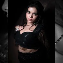 A mid-shot portrait focusing on the texture of the fringed top and the model's direct, confident gaze. The dark, moody lighting enhances the glamour of this studio fashion shot.