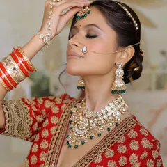 A moment of quiet reflection before the big ceremony. This bride’s look features soft smokey eyes and a neutral lip, perfectly balancing the heavy jewelry and rich red lehenga.