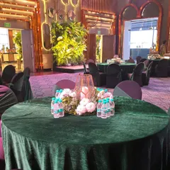 A simple and elegant table setup with a floral centerpiece and a candle lantern on a green velvet tablecloth.