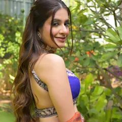 A happy, over-the-shoulder shot showcasing the backless design of the blouse and the soft, wavy hairstyle.