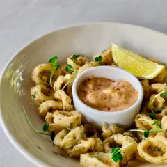 Crispy calamari fritos served with a tangy dipping sauce and a wedge of lime. A classic seaside snack, Granny style.