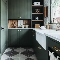 Creating kitchens that depict your personality. This design uses a deep green color for the cabinets, paired with a classic farmhouse sink and patterned floor tiles for a rustic yet sophisticated look.