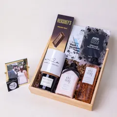 Celebrating the beginning of a forever love story with this elegant hamper for a newlywed couple. It includes 'Love Story' bath products, a personalized mug with the couple's names, a scented candle, and a framed photo to capture their special moment.