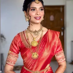 A radiant South Indian bride in a stunning red silk saree. The makeup features a classic red lip and defined eyes, perfect for her wedding day.