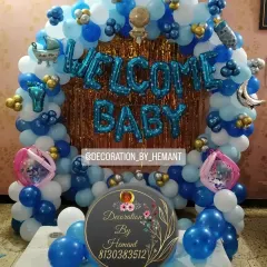 Welcoming a baby boy with a classic blue and white balloon decoration. This arch setup includes a metallic fringe backdrop, "Welcome Baby" foil balloons, and cute baby-themed accents, perfect for photos at home.